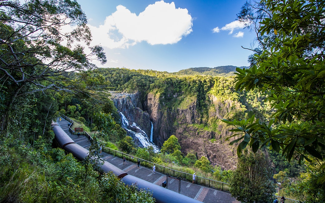 Kuranda Scenic Railway passing by Barron Falls in lush rainforest setting.