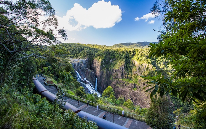 Kuranda Scenic Railway passing by Barron Falls in lush rainforest setting.