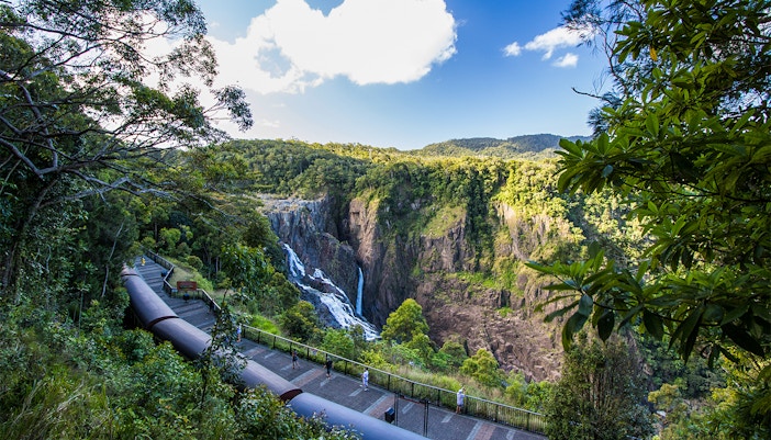 Kuranda Scenic Railway passing by Barron Falls in lush rainforest setting.