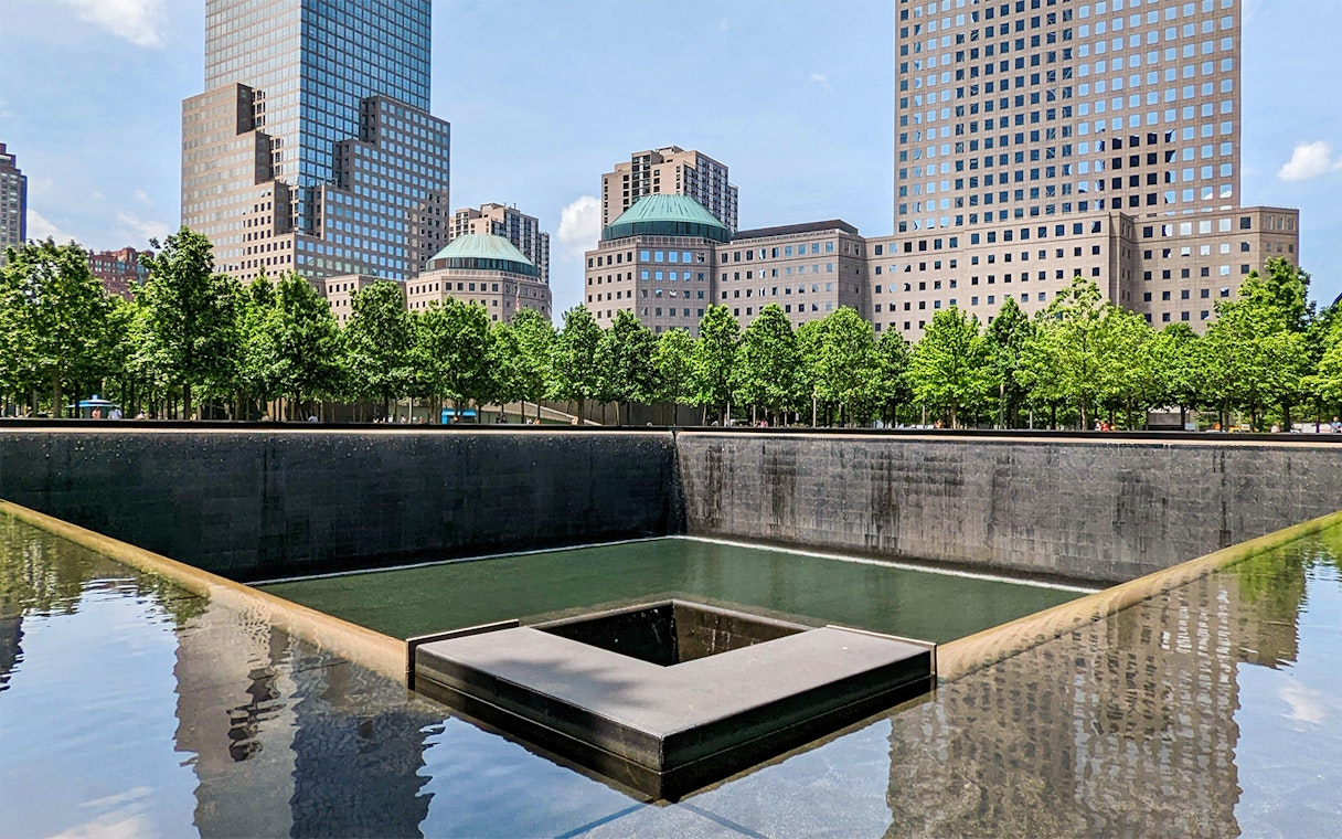 9/11 Memorial reflecting pool with surrounding skyscrapers in New York City.