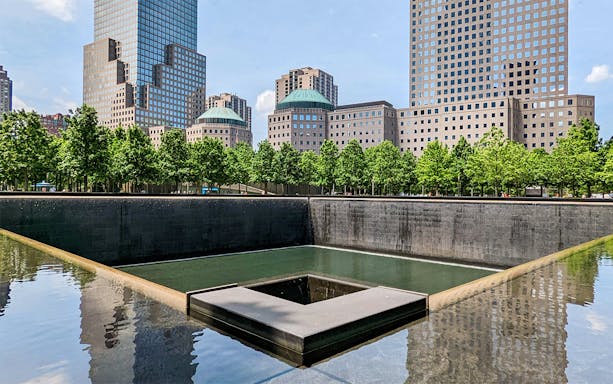 9/11 Memorial reflecting pool with surrounding skyscrapers in New York City.