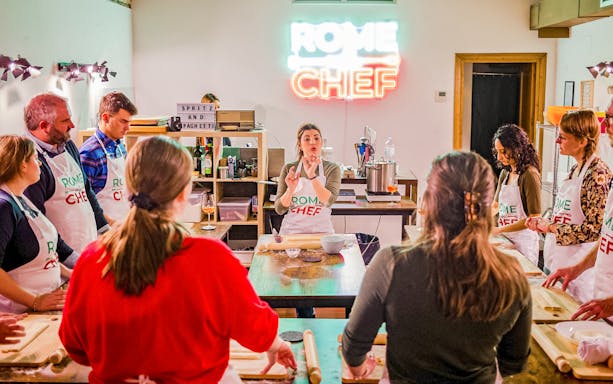 Participants in a Spritz & Spaghetti cooking class in Rome, guided by an instructor.