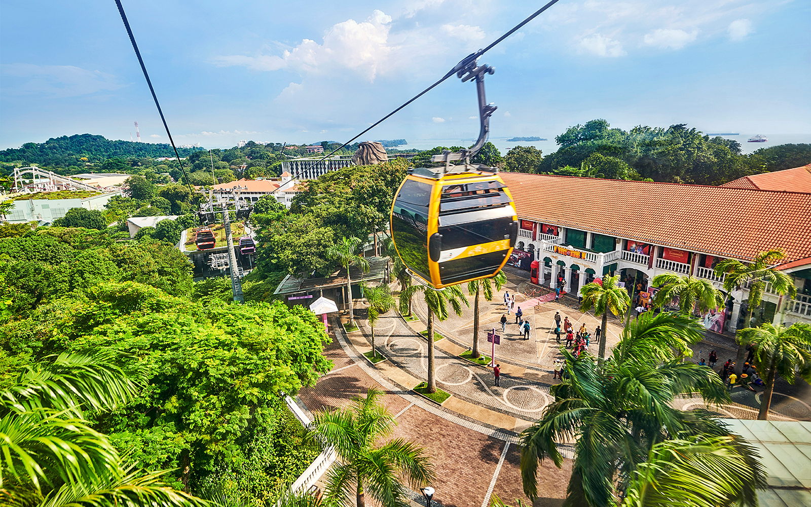 Cable cars over Sentosa Island with Singapore skyline in the background.
