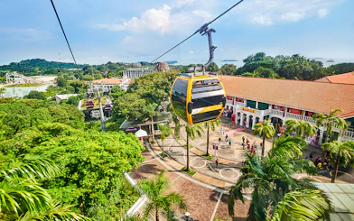 Cable cars over Sentosa Island with Singapore skyline in the background.