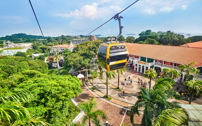 Cable cars over Sentosa Island with Singapore skyline in the background.