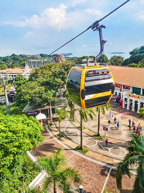 Cable cars over Sentosa Island with Singapore skyline in the background.