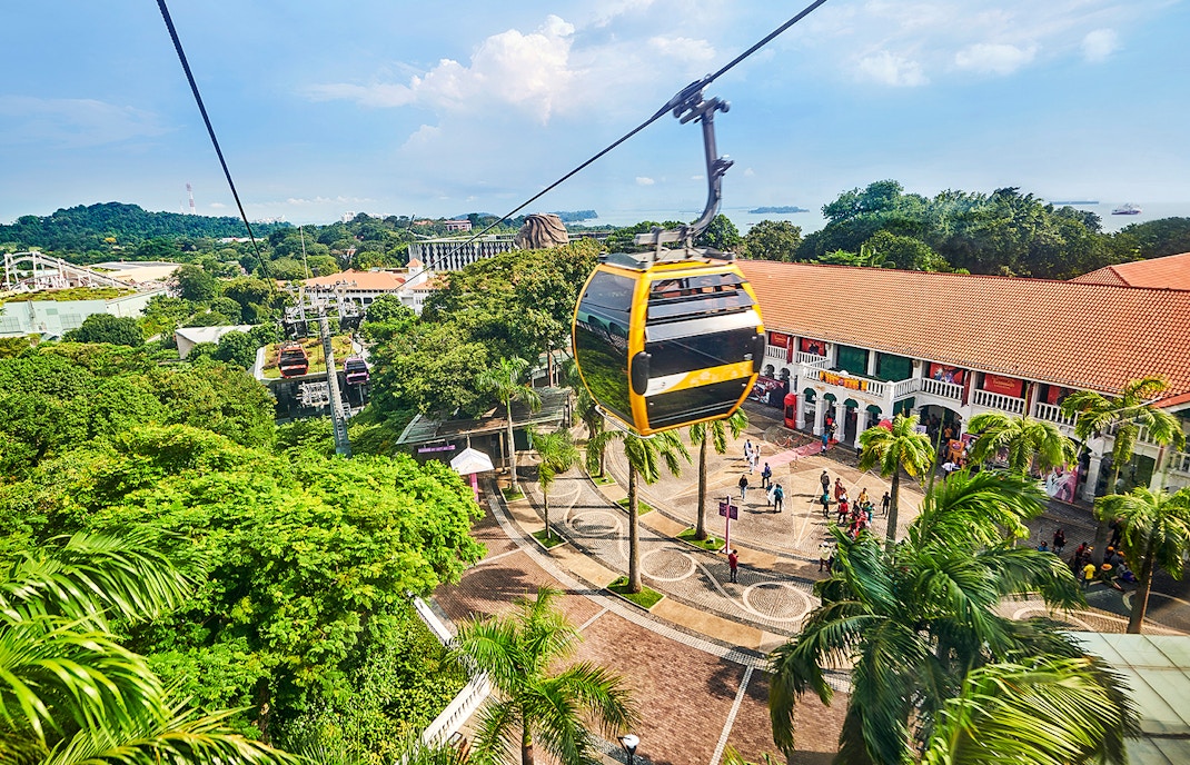 Cable cars over Sentosa Island with Singapore skyline in the background.
