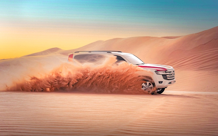 SUV driving through sand dunes during Abu Dhabi evening desert safari.