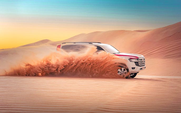 SUV driving through sand dunes during Abu Dhabi evening desert safari.