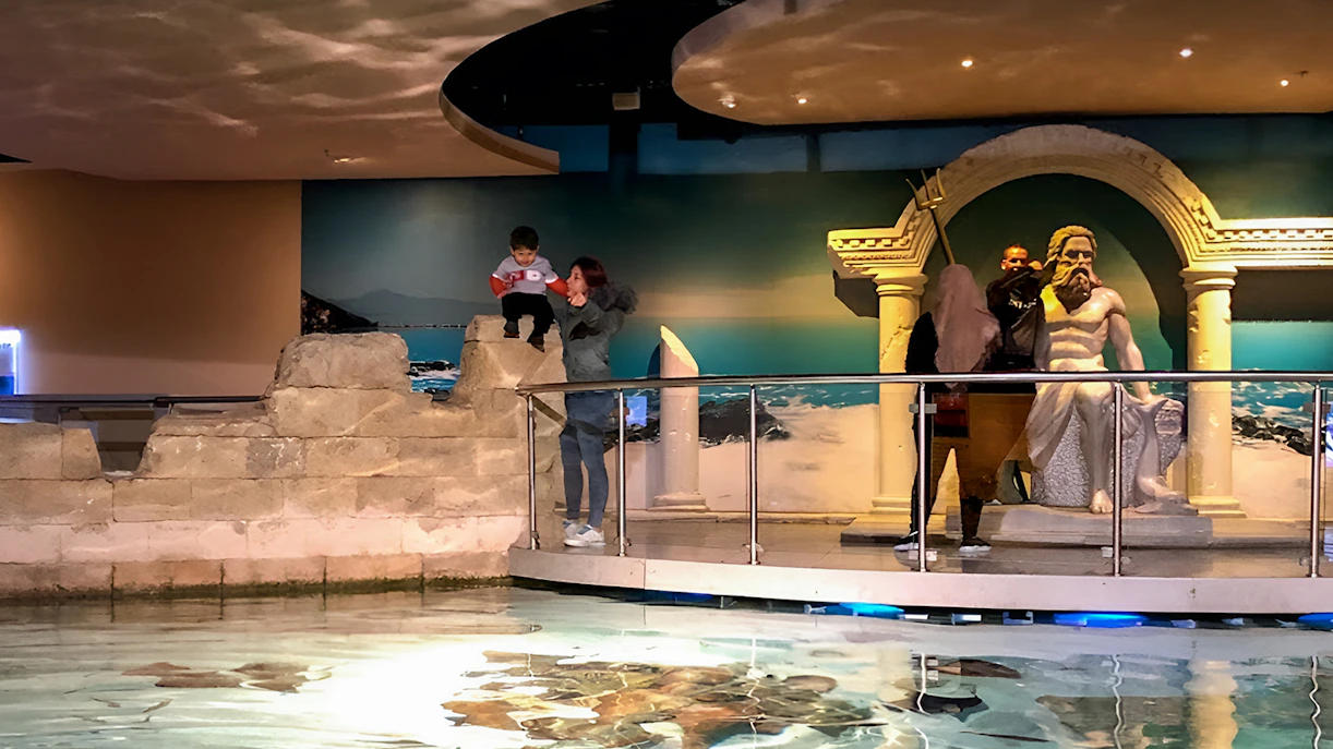 Visitors exploring the Istanbul Aquarium near a Poseidon statue.