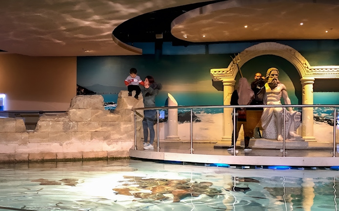 Visitors exploring the Istanbul Aquarium near a Poseidon statue.