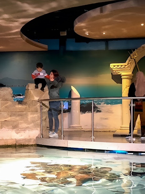 Visitors exploring the Istanbul Aquarium near a Poseidon statue.