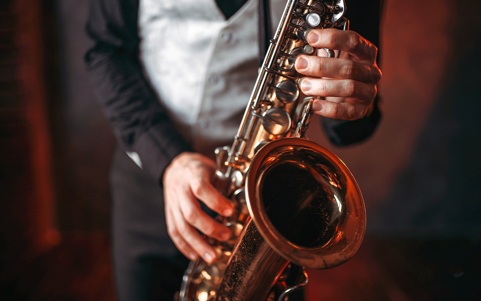 Saxophonist playing a brass saxophone in a dimly lit setting.