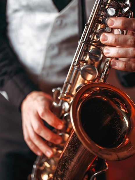 Saxophonist playing a brass saxophone in a dimly lit setting.