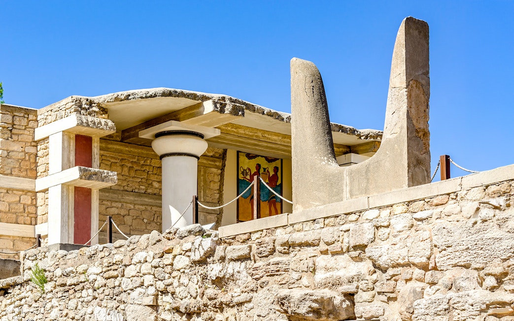 Bulls Horns sculpture at Knossos Palace, Crete, with ancient fresco in background.