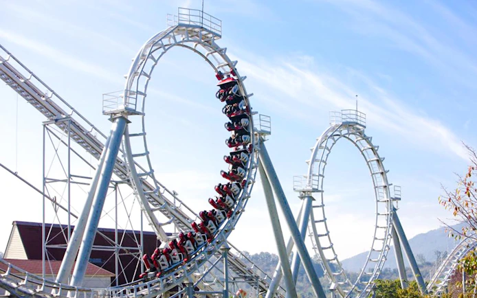 Steel roller coaster with multiple loops against a clear sky.