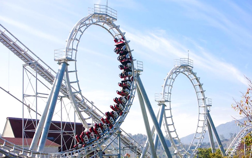 Steel roller coaster with multiple loops against a clear sky.
