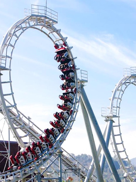 Steel roller coaster with multiple loops against a clear sky.