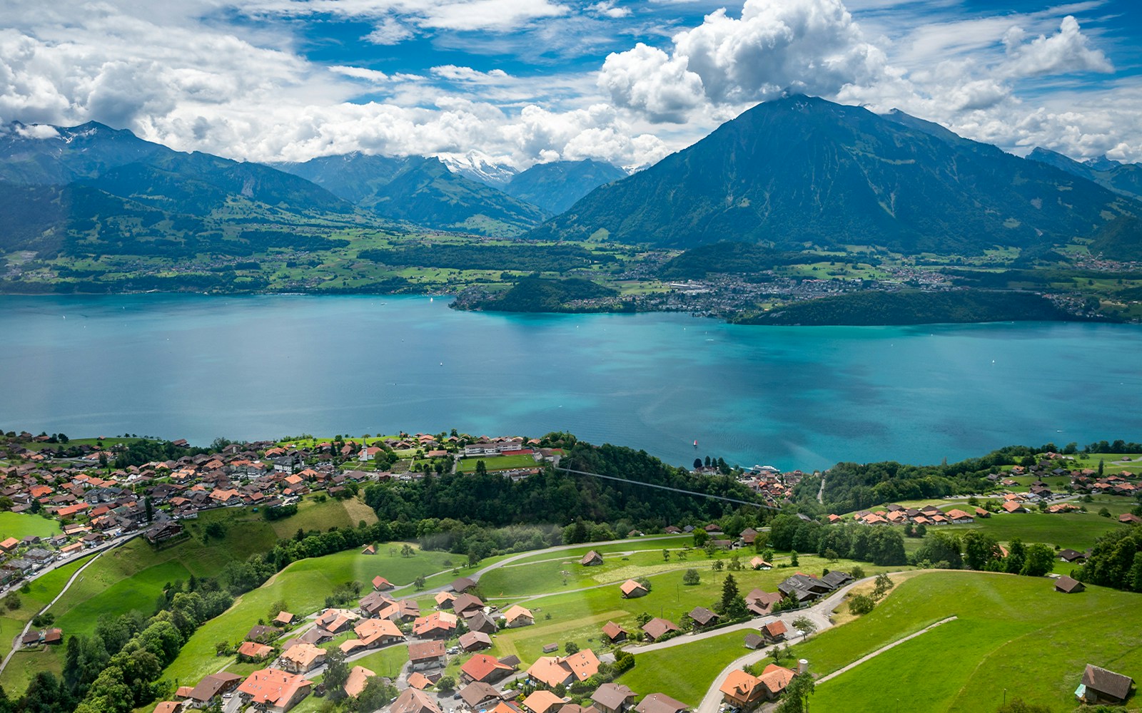 Aerial view of Lake Thun with surrounding Swiss Alps and villages.
