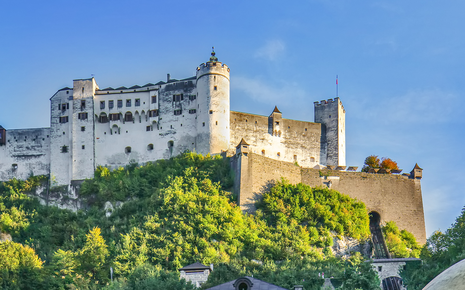 Salzburg Hohensalzburg fortress on a hill with lush greenery.