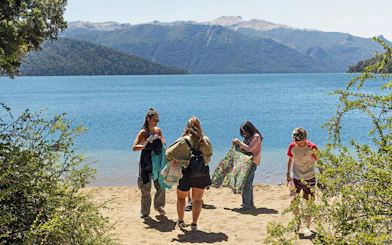 Travelers at a lakeside viewpoint in Patagonia with mountain backdrop.