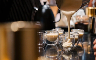 Pouring creamy Vietnamese egg coffee into glass cups.
