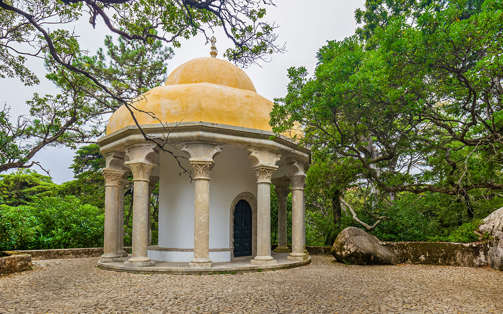 Columned temple at Pena Palace surrounded by lush greenery in Sintra, Portugal.