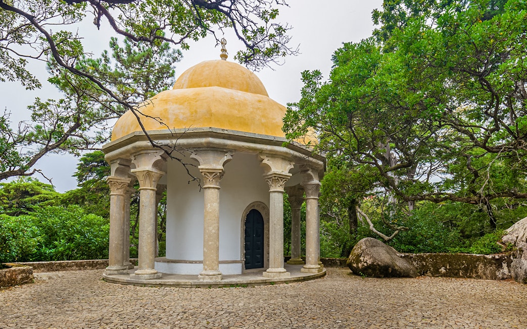 Columned temple at Pena Palace surrounded by lush greenery in Sintra, Portugal.