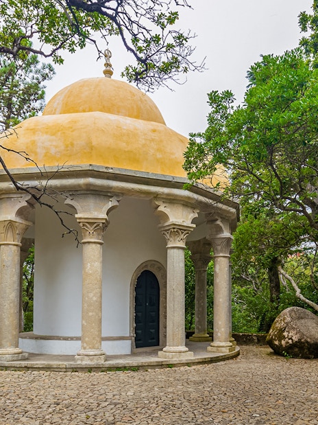 Columned temple at Pena Palace surrounded by lush greenery in Sintra, Portugal.