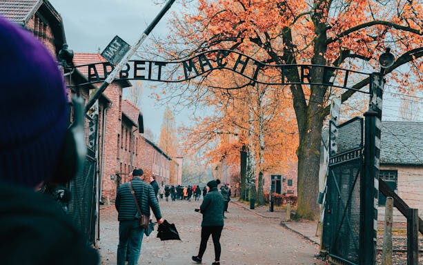 Visitors entering Auschwitz-Birkenau under the "Arbeit Macht Frei" gate during a guided tour.