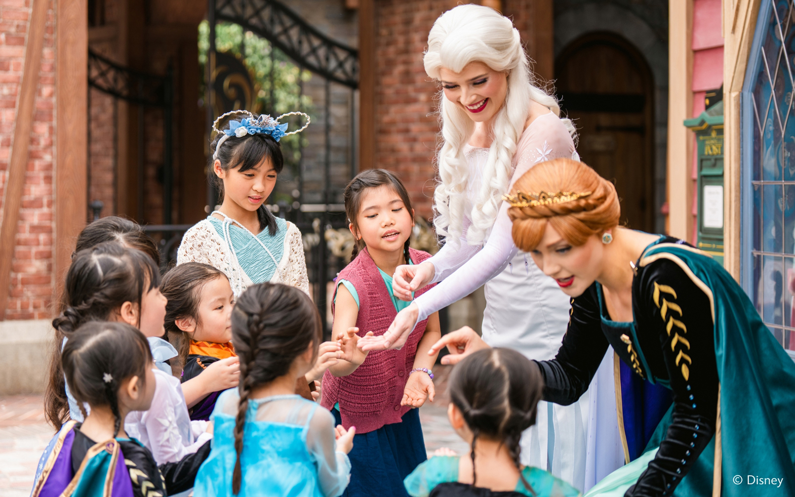 Elsa and Anna interacting with children at Disneyland Hong Kong's Frozen Ever After attraction.