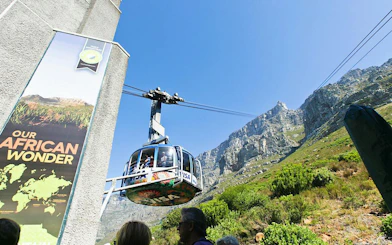 Cable car ascending Table Mountain, Cape Town, with rocky cliffs in the background.