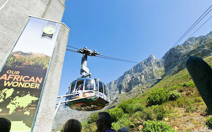 Cable car ascending Table Mountain, Cape Town, with rocky cliffs in the background.
