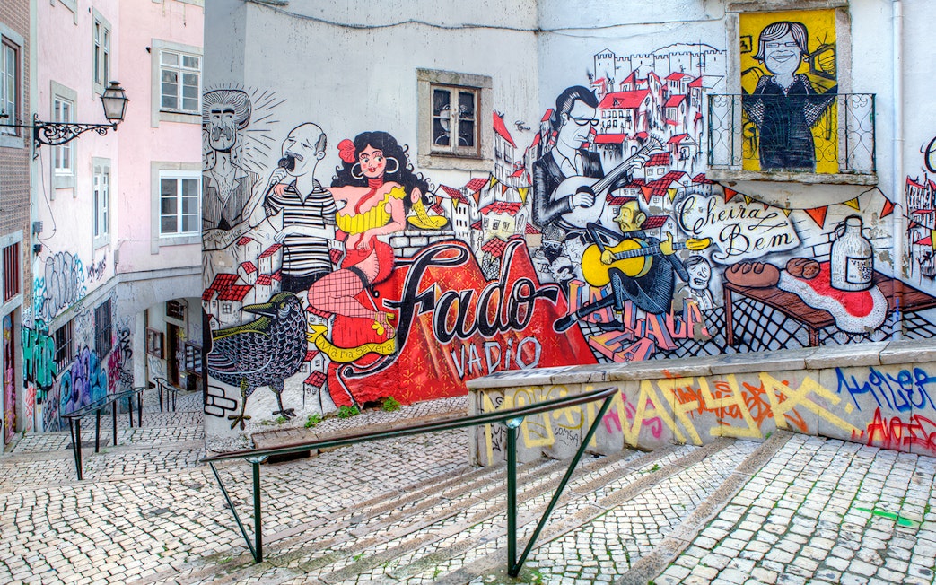 Fado-themed street art on a Lisbon alley wall, featuring musicians and vibrant cityscape.