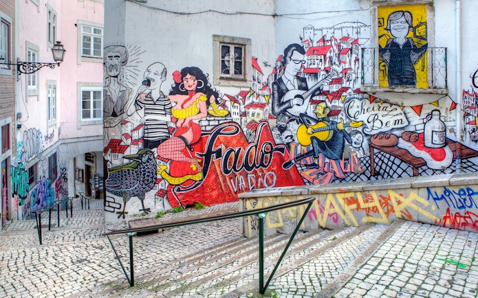 Fado-themed street art on a Lisbon alley wall, featuring musicians and vibrant cityscape.