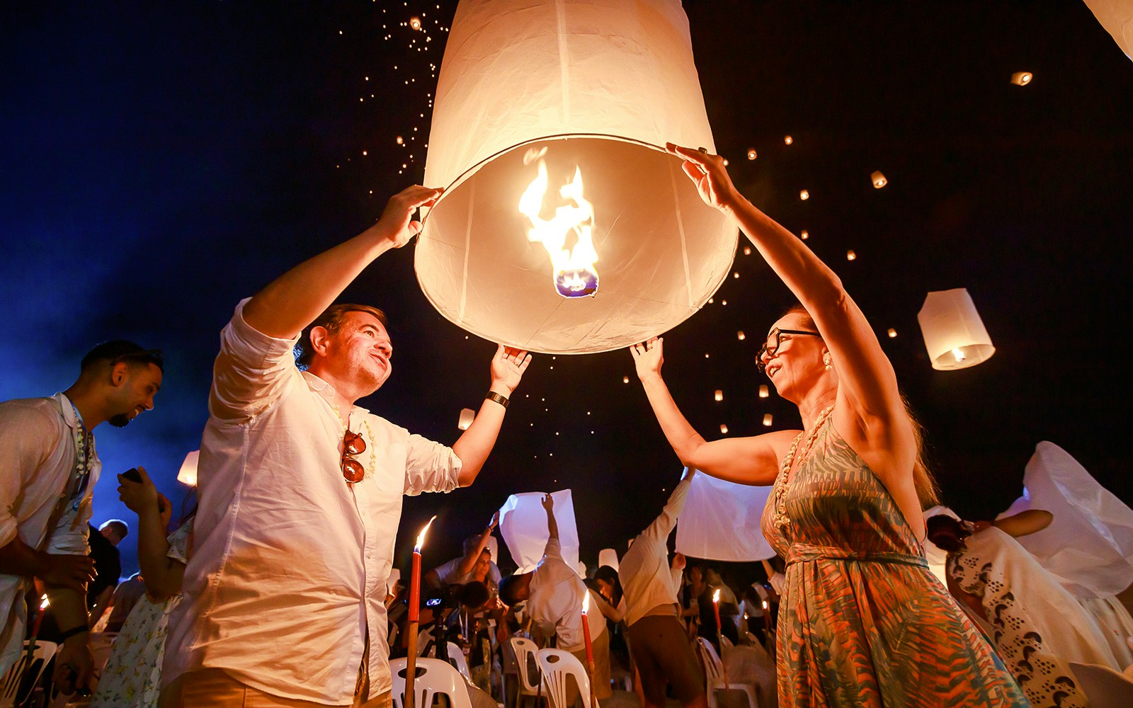 Releasing a sky lantern at Chiang Mai Sky Lanterns Festival, Thailand, with a crowd in the background.