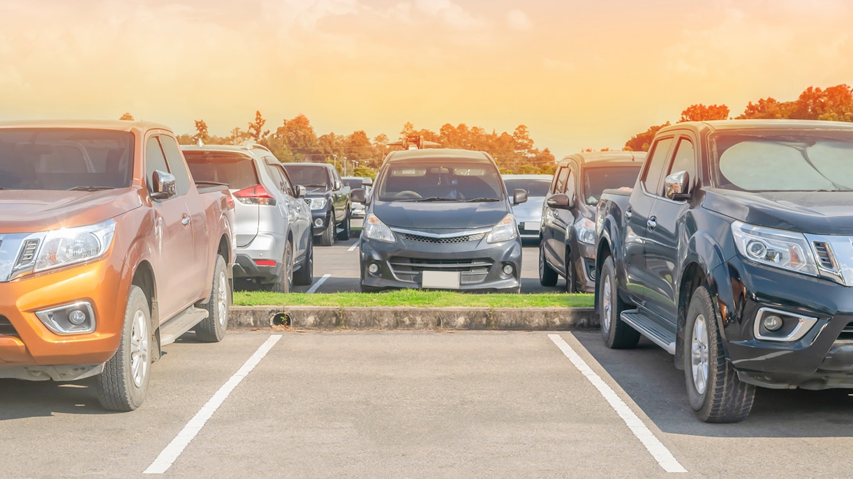 Parking lot with multiple cars under a sunset sky.