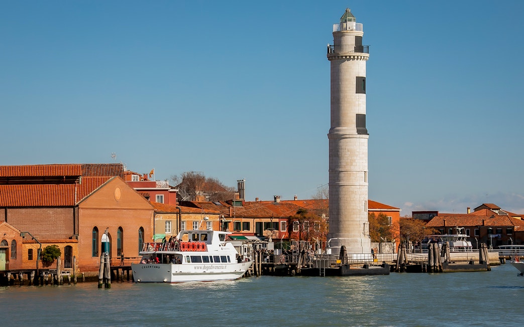 Vaporetto near Murano Lighthouse in Venice with museum buildings in the background.