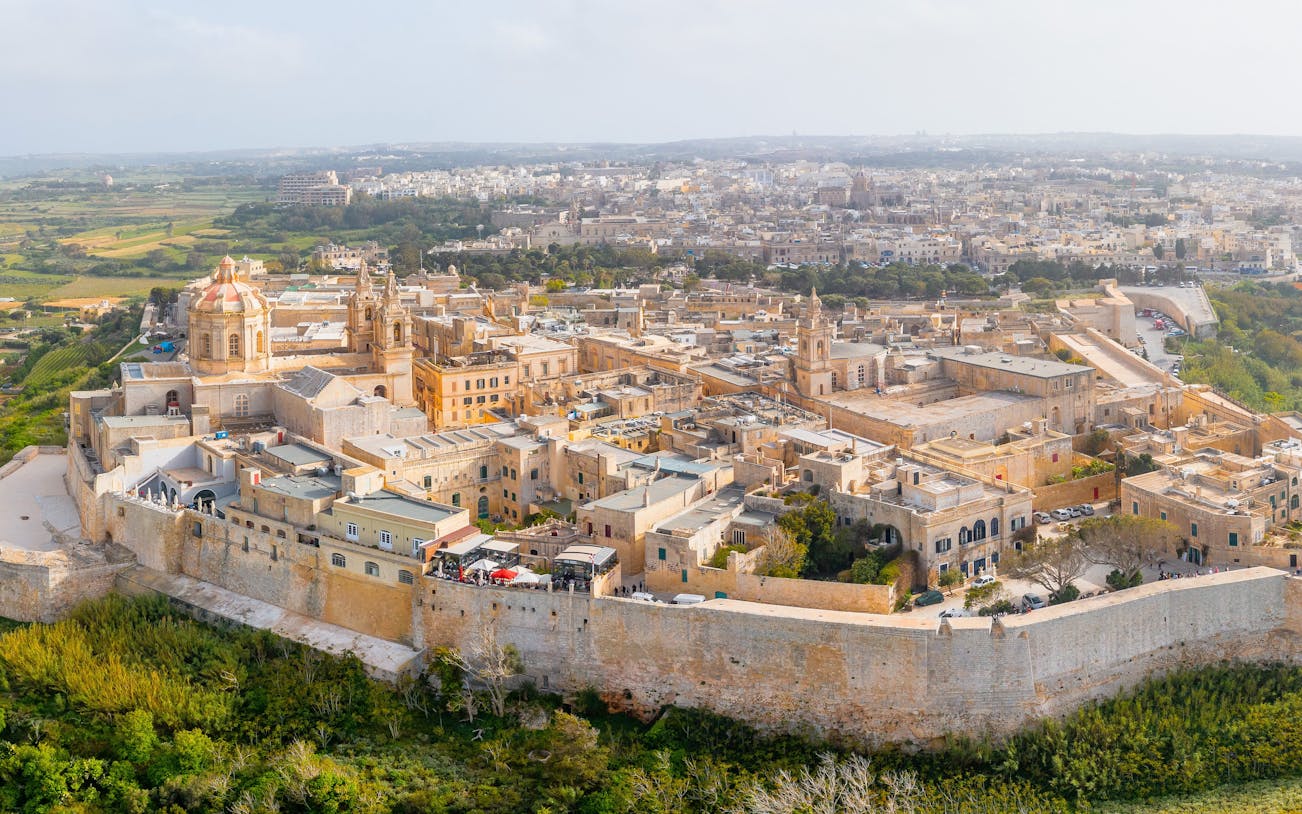 Aerial view of Mdina, Malta's ancient walled city, showcasing historic architecture and surrounding landscape.