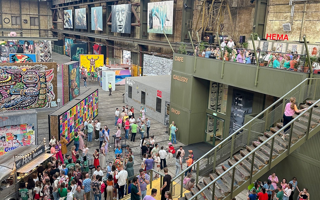 Visitors exploring vibrant street art displays inside Straat Museum, Amsterdam.