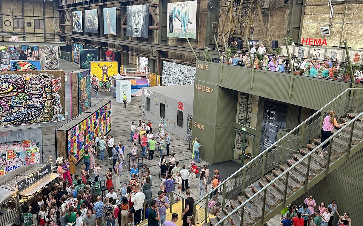 Visitors exploring vibrant street art displays inside Straat Museum, Amsterdam.