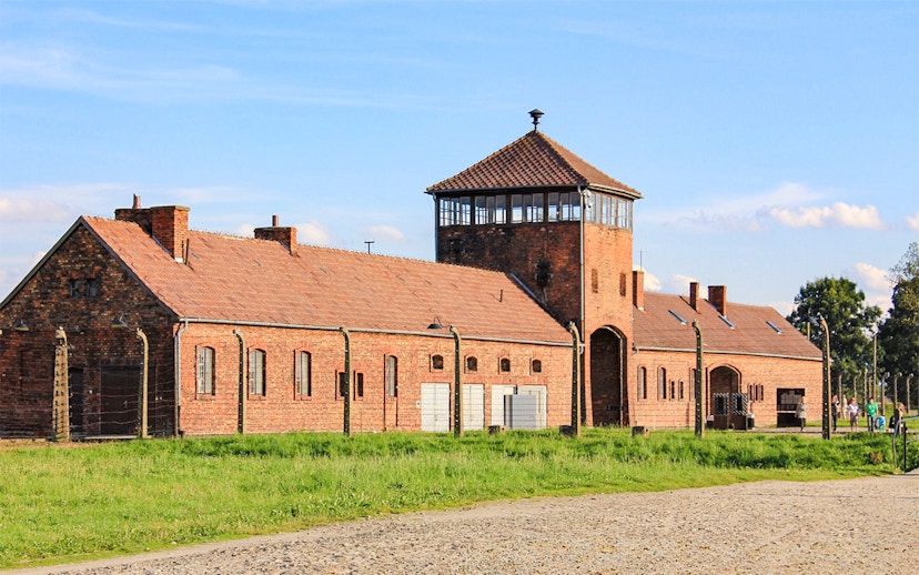 Auschwitz Birkenau II entrance gate with brick buildings and watchtower.