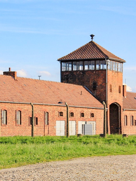 Auschwitz Birkenau II entrance gate with brick buildings and watchtower.