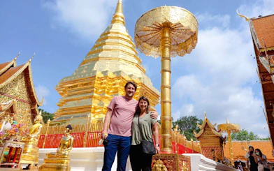 Golden pagoda at Wat Phra That Doi Suthep, Chiang Mai, with tourists exploring the temple grounds.