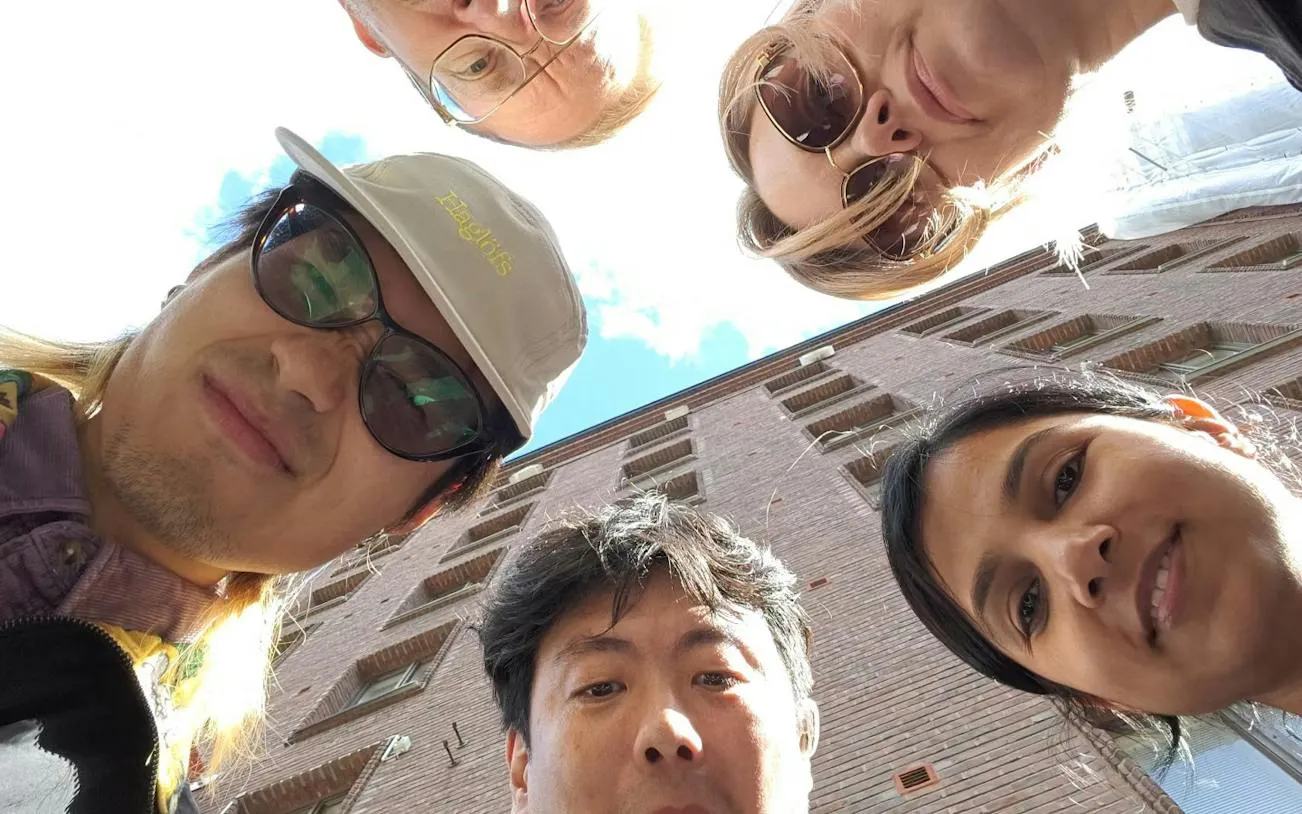 Participants gather for Helsinki Murder Mystery game near a brick building.