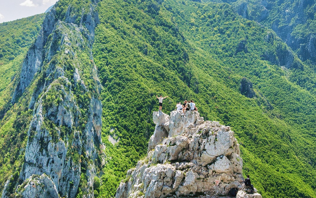 Hikers on Gamti Mountain summit with lush green landscape.