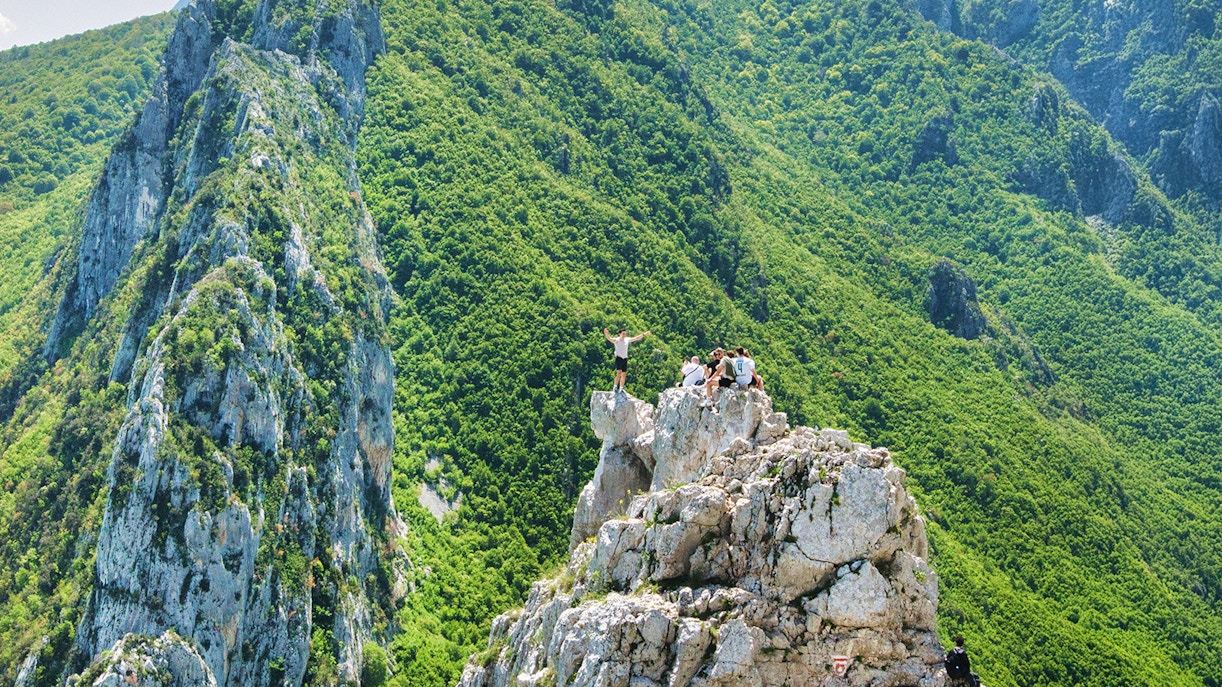 Hikers on Gamti Mountain summit with lush green landscape.