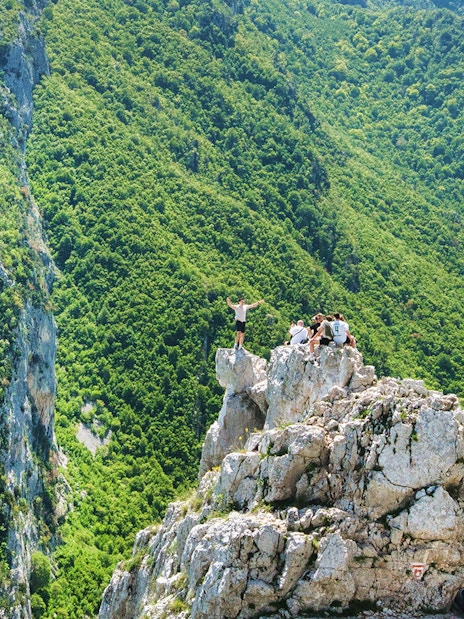 Hikers on Gamti Mountain summit with lush green landscape.