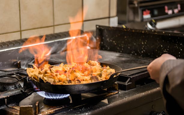 Cooking Kaiserschmarrn on a stove during a traditional cooking class.