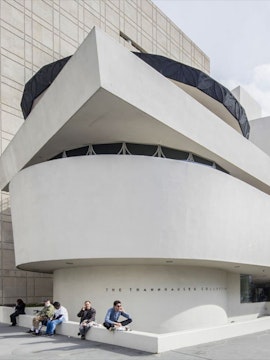 Guggenheim Museum exterior with visitors sitting near the Thannhauser Collection entrance.